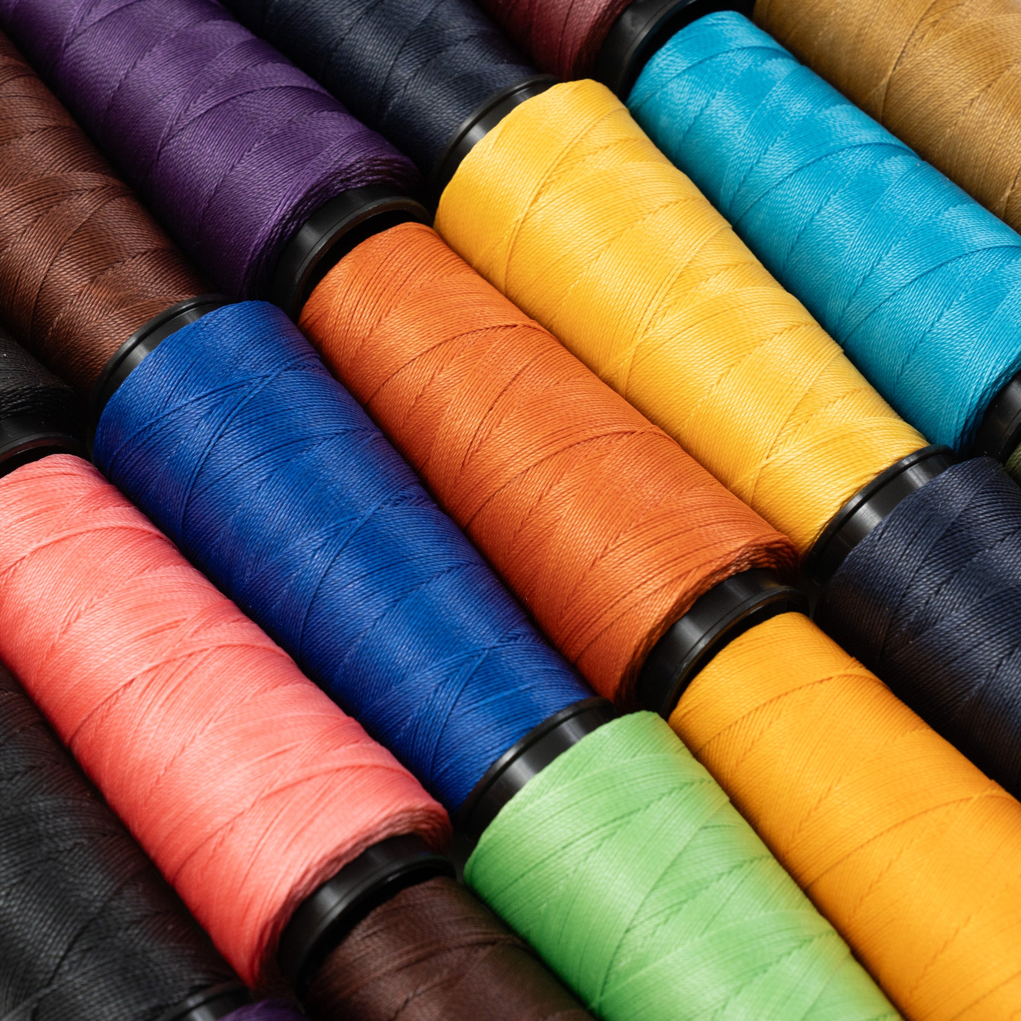 Close-up view of MBT waxed polyester thread spools in assorted colors