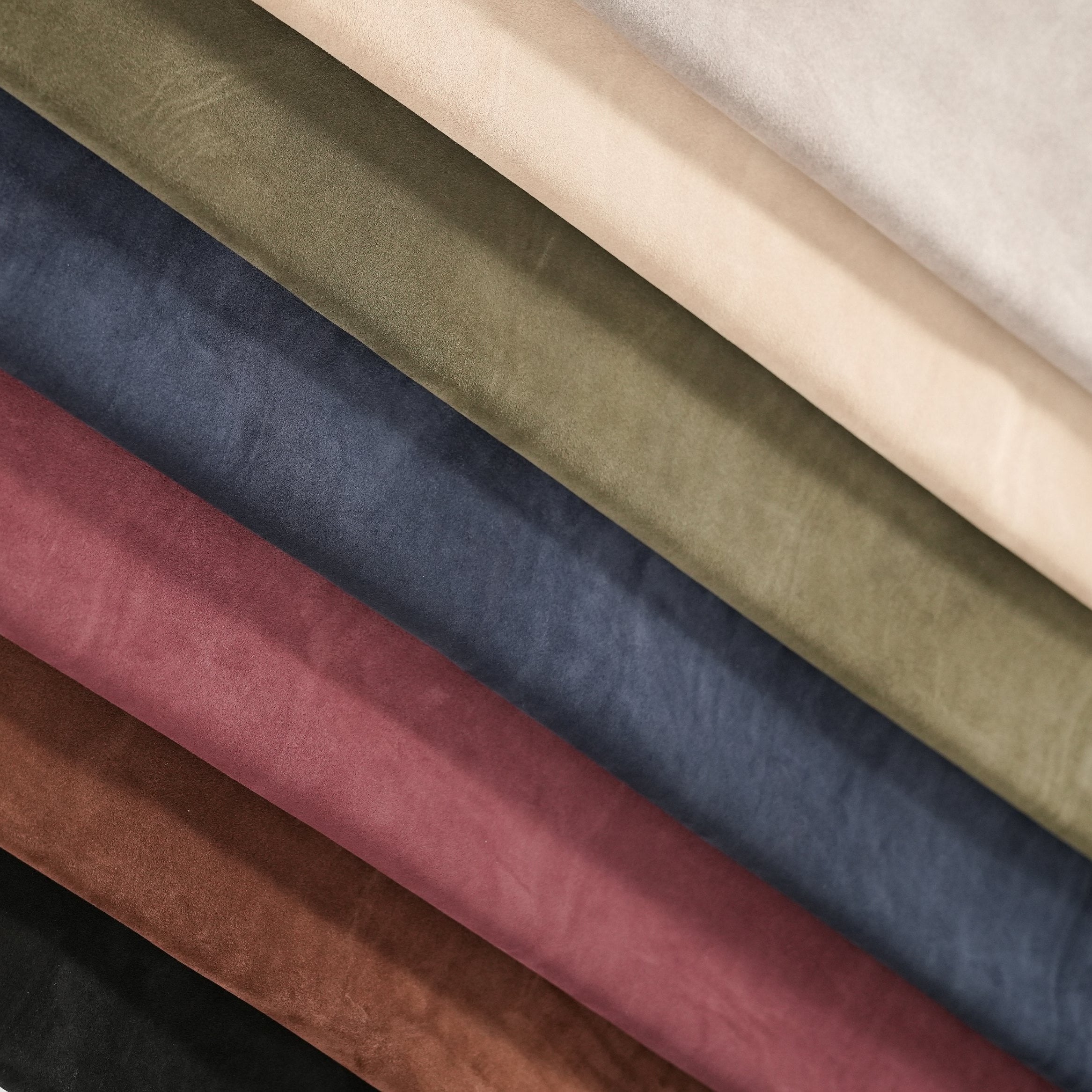 Collection of different colored cowhide suede hides arranged in a row.