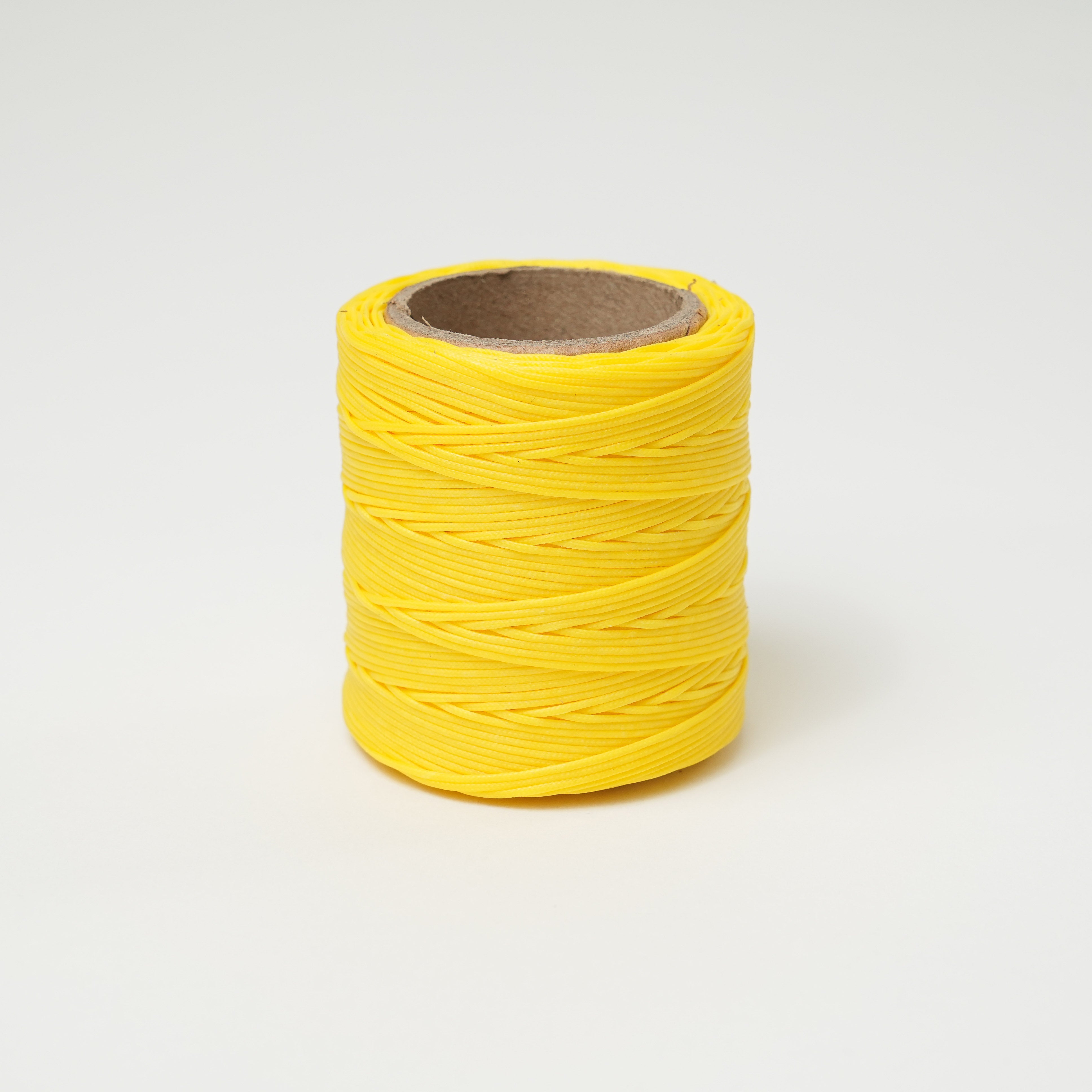 Canary yellow spool of thread on a white background