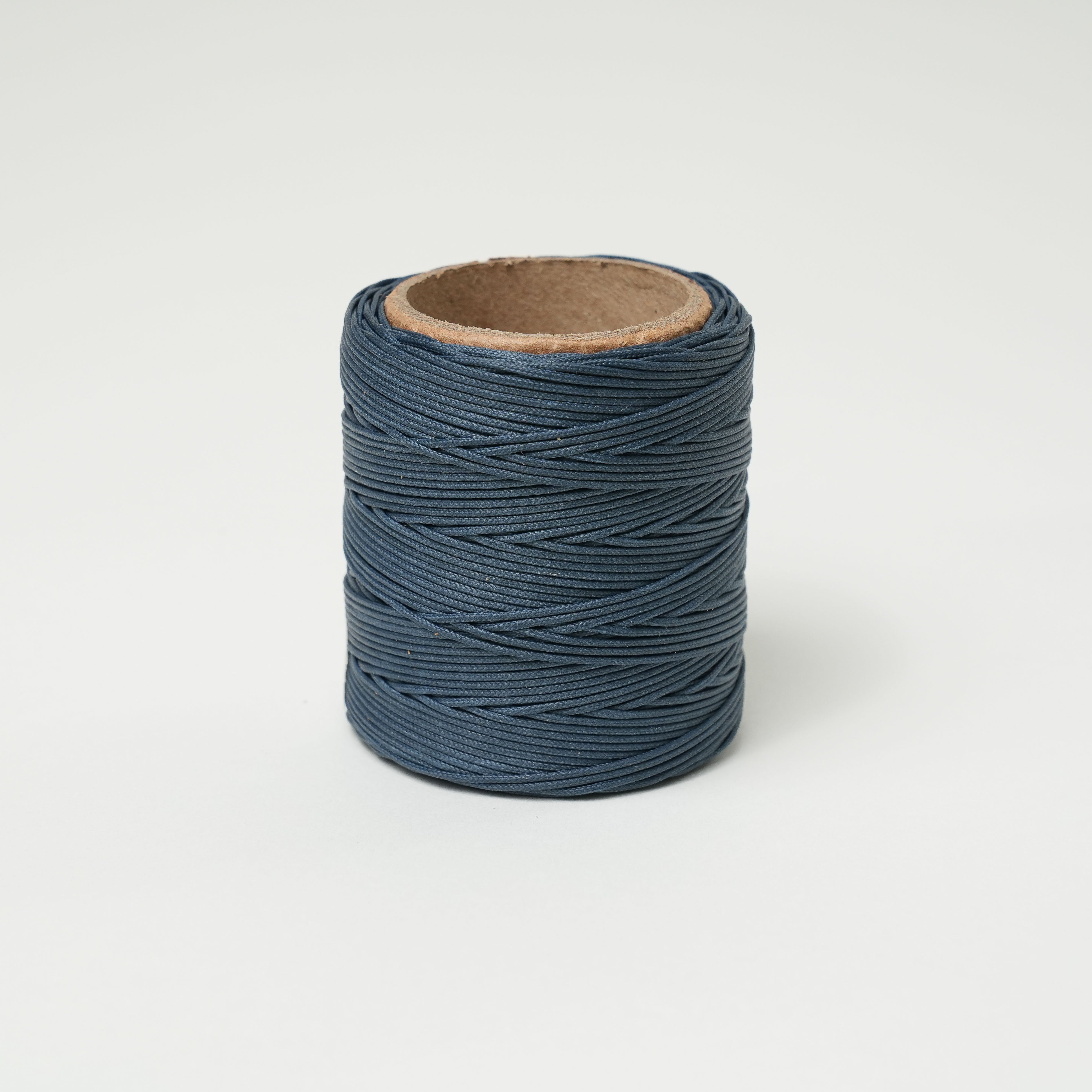 Spool of dusk dark blue thread on a white background