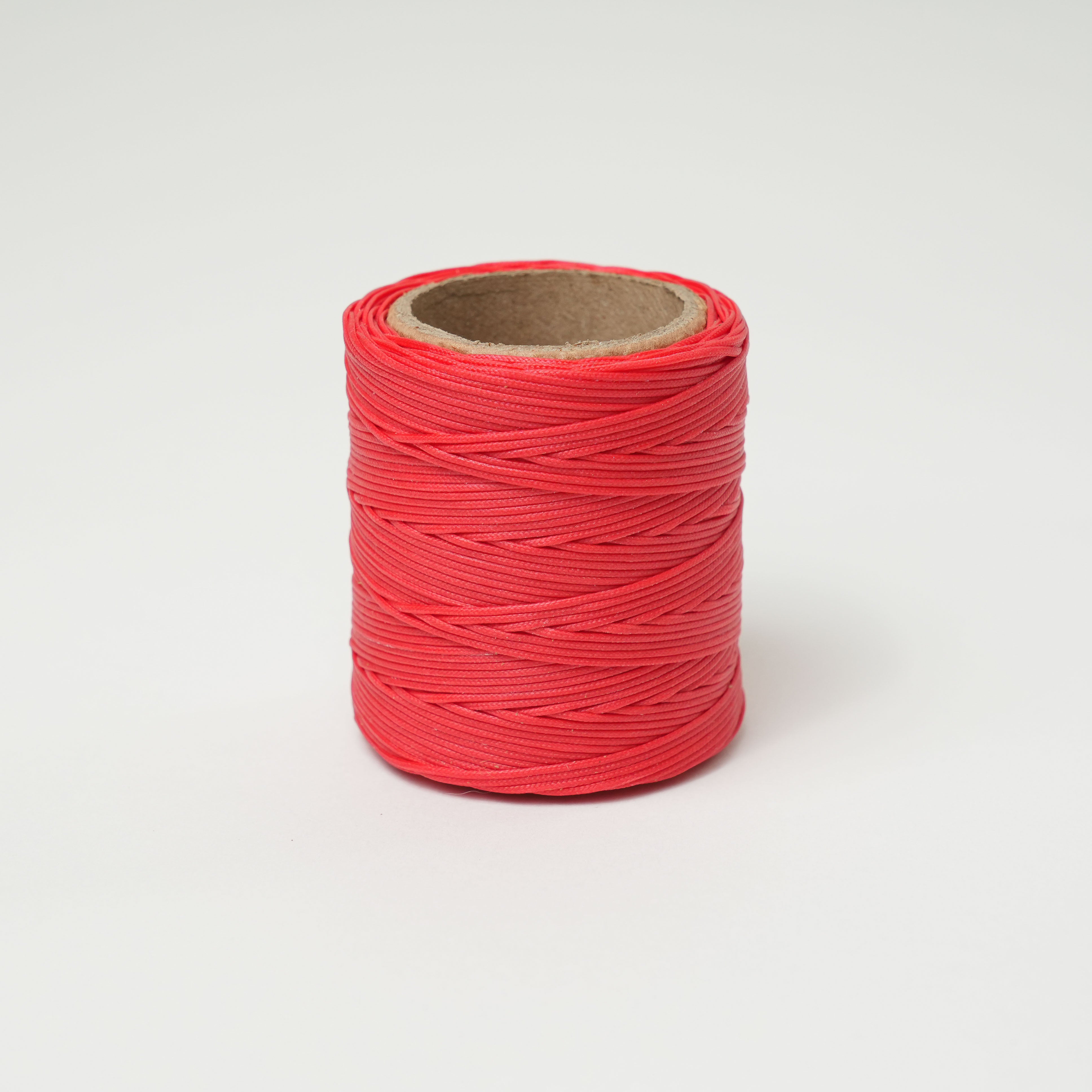 Fireball red spool of thread on a light gray background