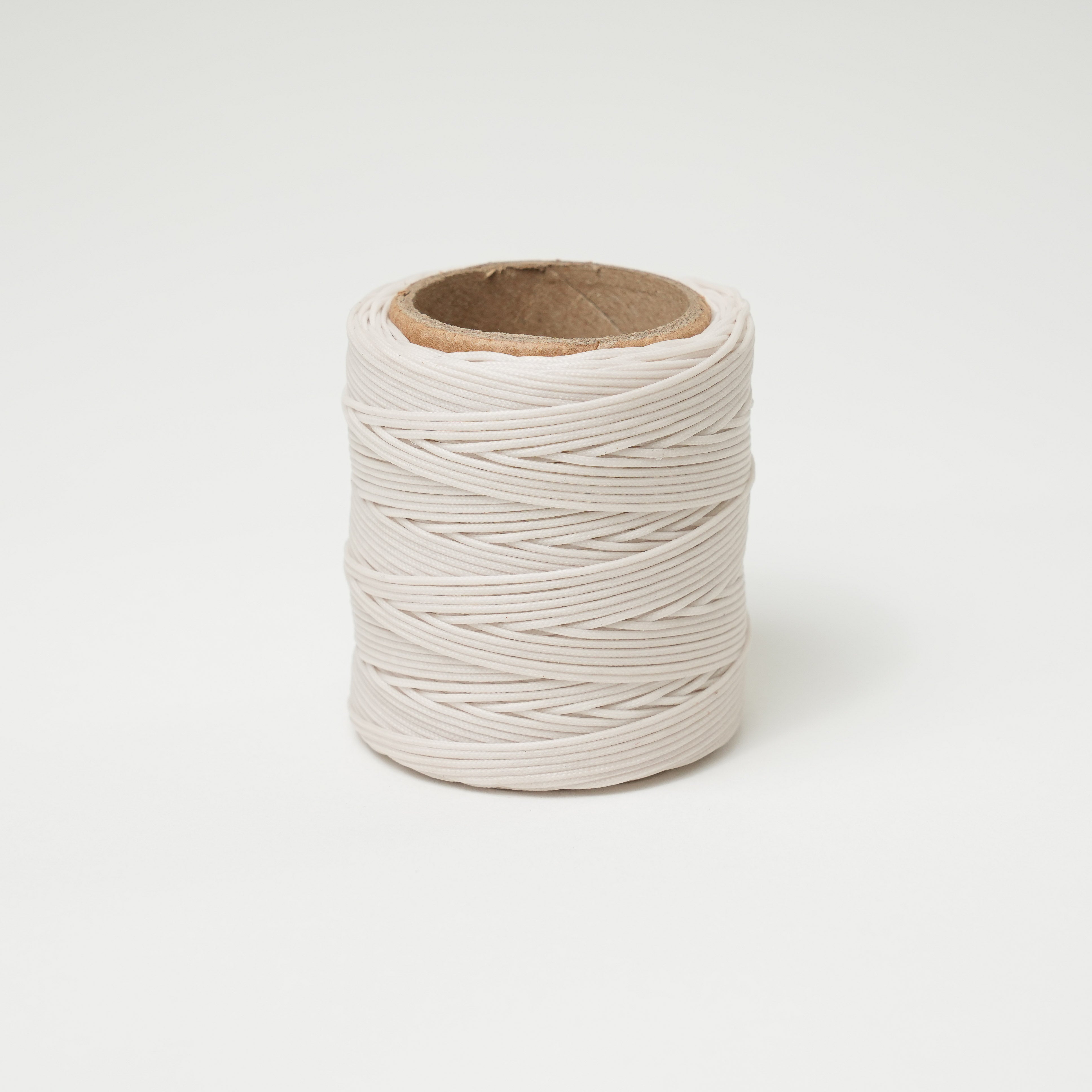 Spool of ivory thread on a light gray background