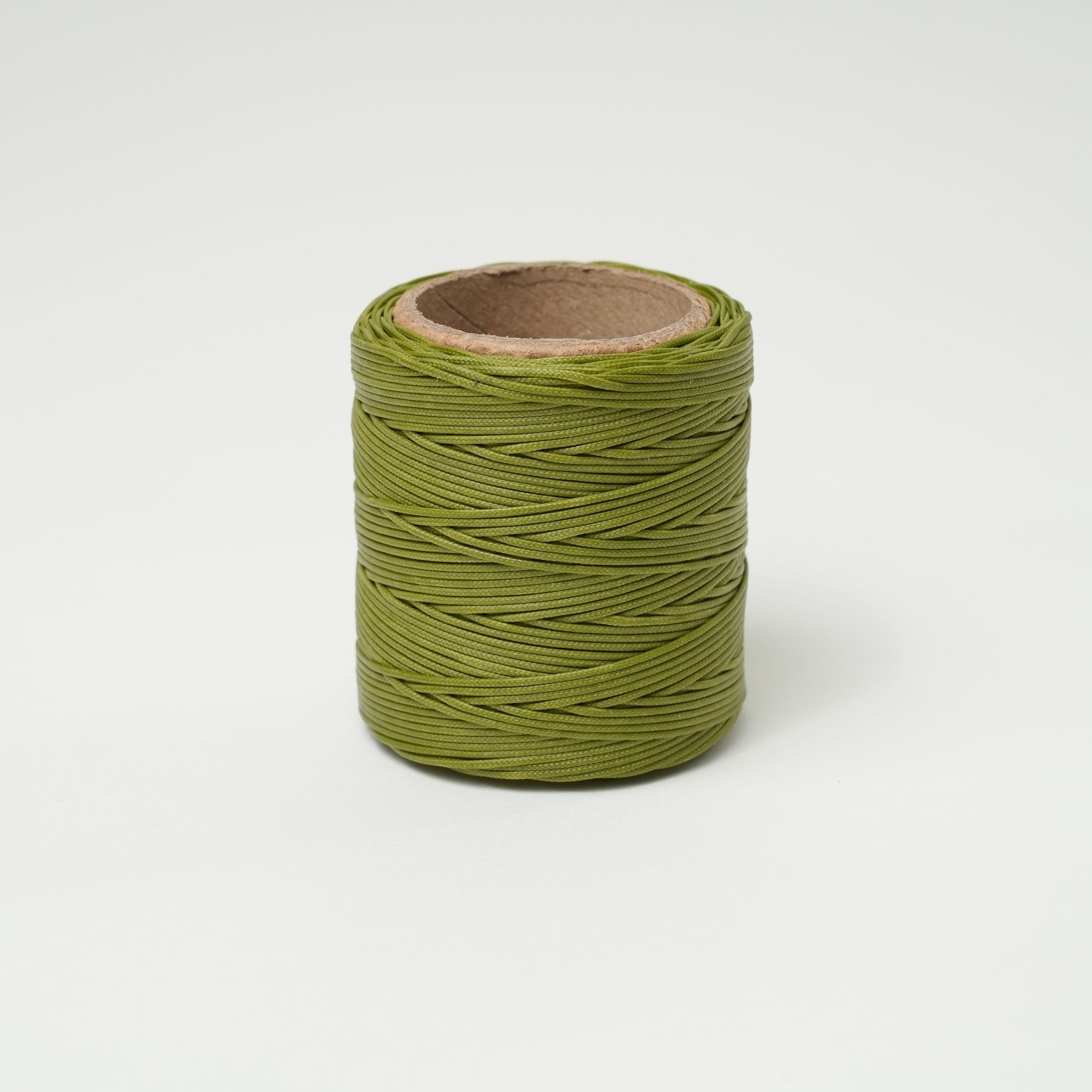 Roll of olive green thread on a white background