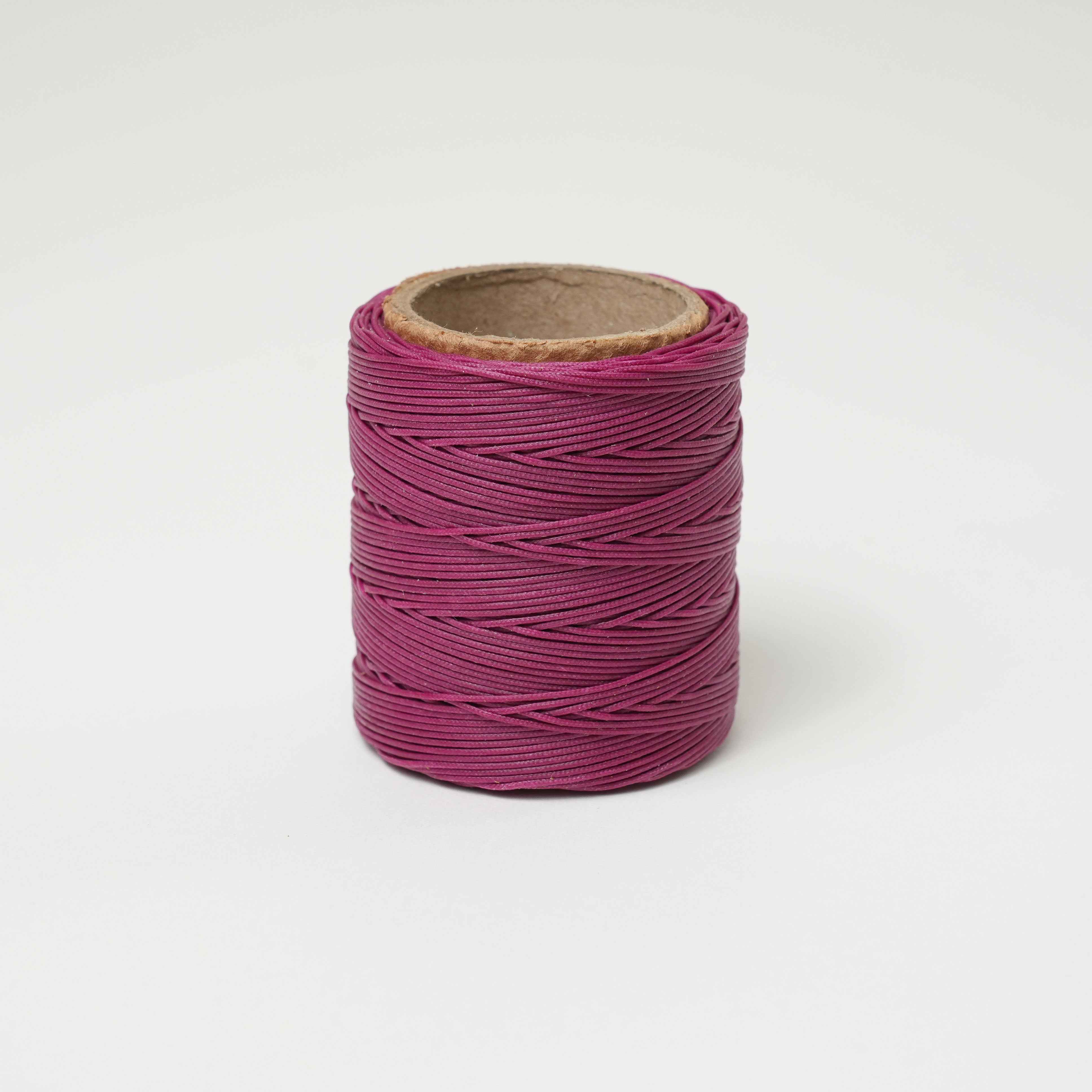 Spool of plum thread on a white background