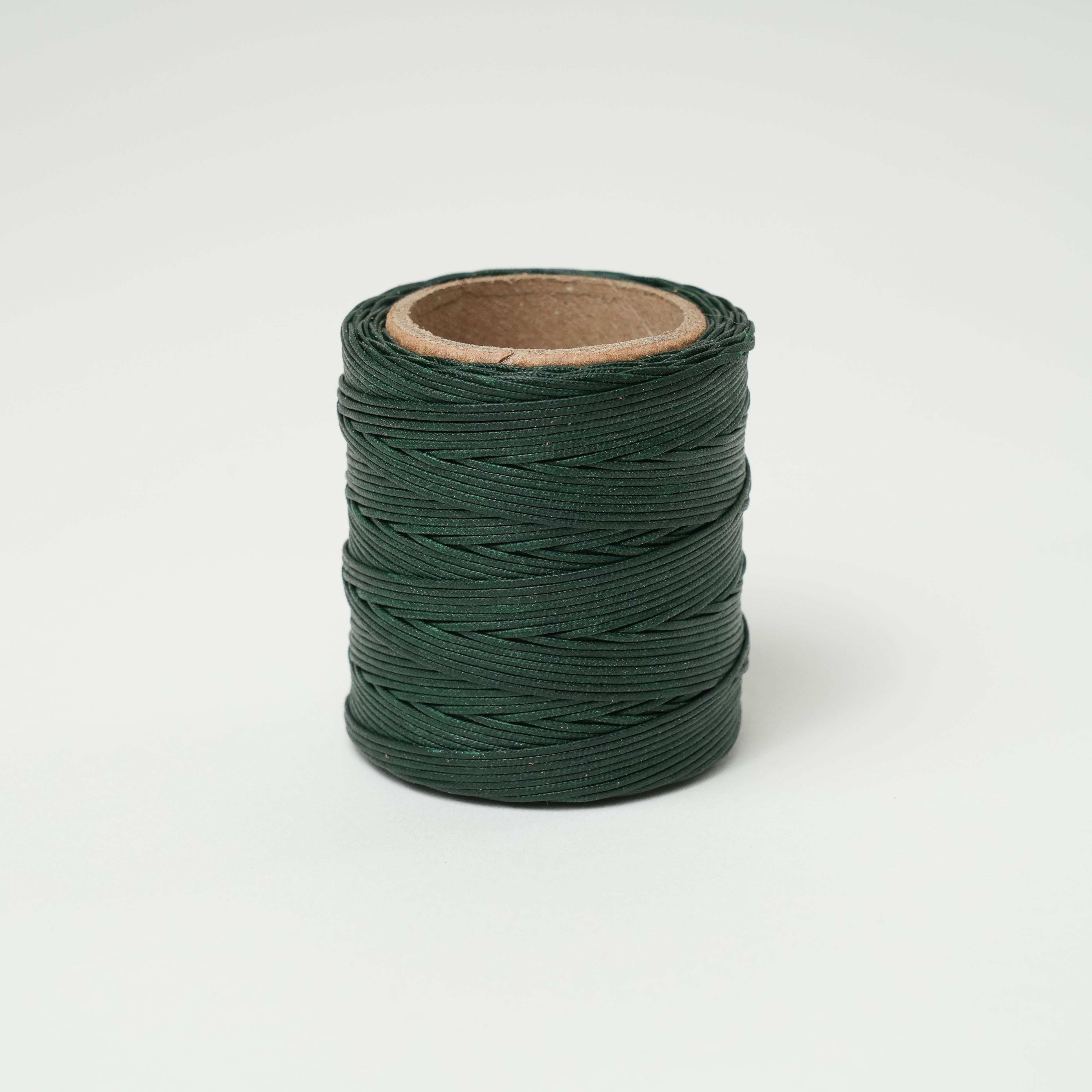Roll of spruce green thread on a white background